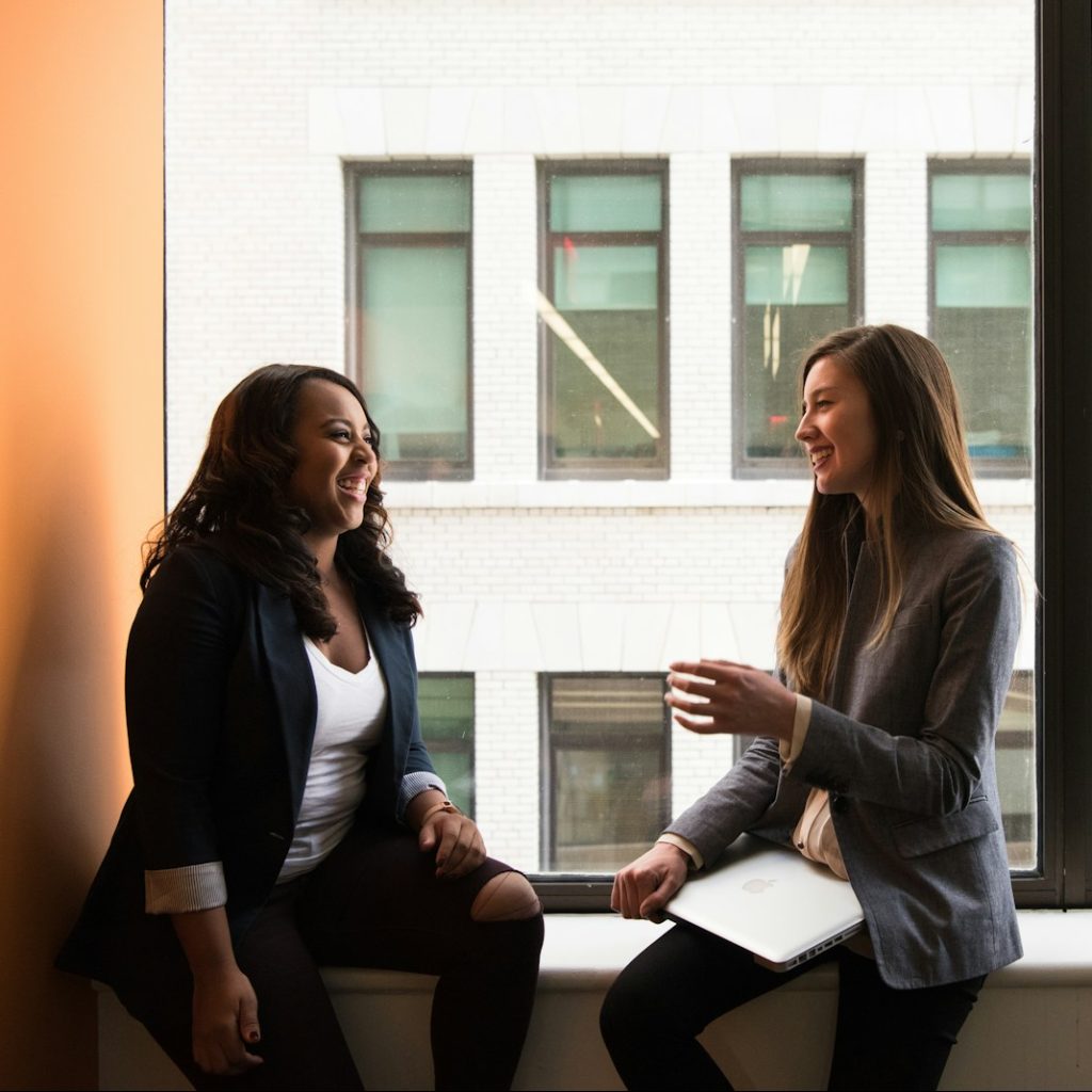 Photo by Christina @ wocintechchat.com two woman sitting by the window laughing